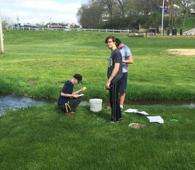 Student testing water at the park